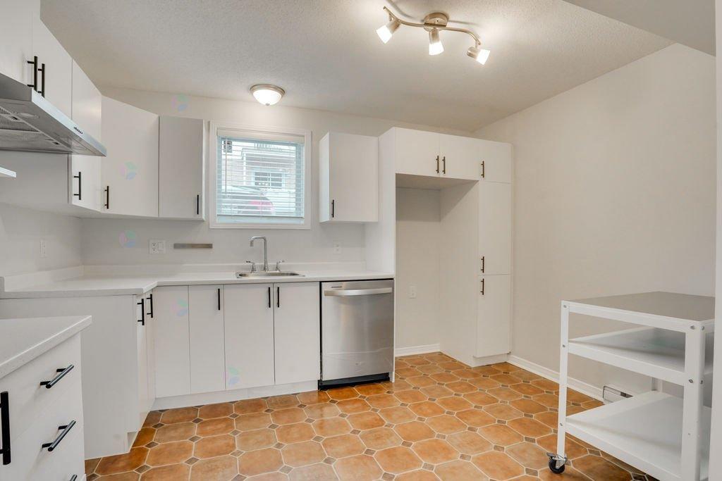 A kitchen with white cabinets and a tile floor.