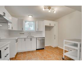 A kitchen with white cabinets and a tile floor.