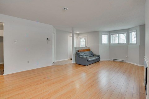 A living room with a grey couch and wooden floors.