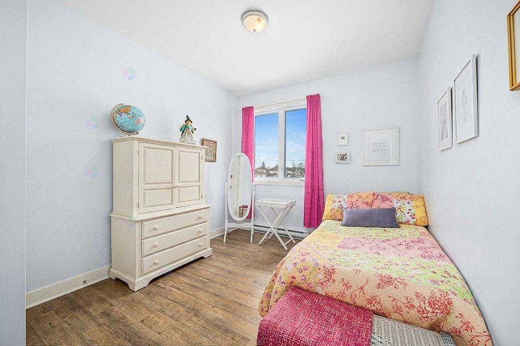 A bedroom with a bed, a dresser, and a chair.