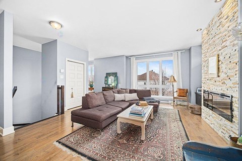 A living room with a brown couch and a rug.