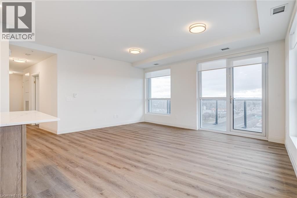 A spacious room with wooden flooring and large windows.
