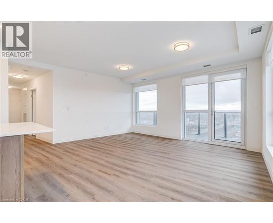 A spacious room with wooden flooring and large windows.