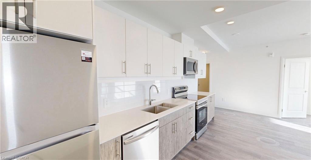 A modern kitchen with a refrigerator, microwave, and oven.