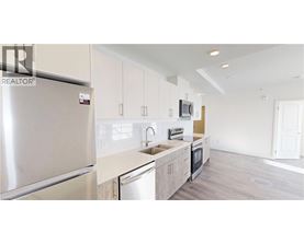 A modern kitchen with a refrigerator, microwave, and oven.