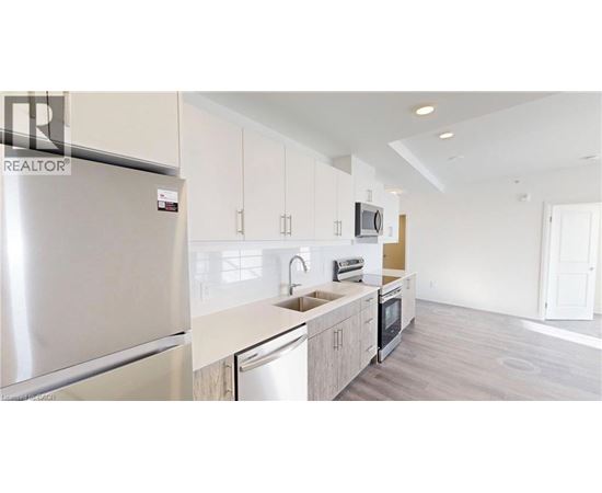 A modern kitchen with a refrigerator, microwave, and oven.