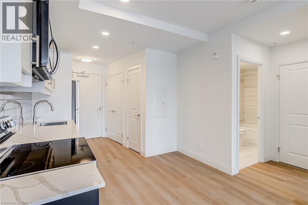 A modern kitchen with white cabinets and a wooden floor.