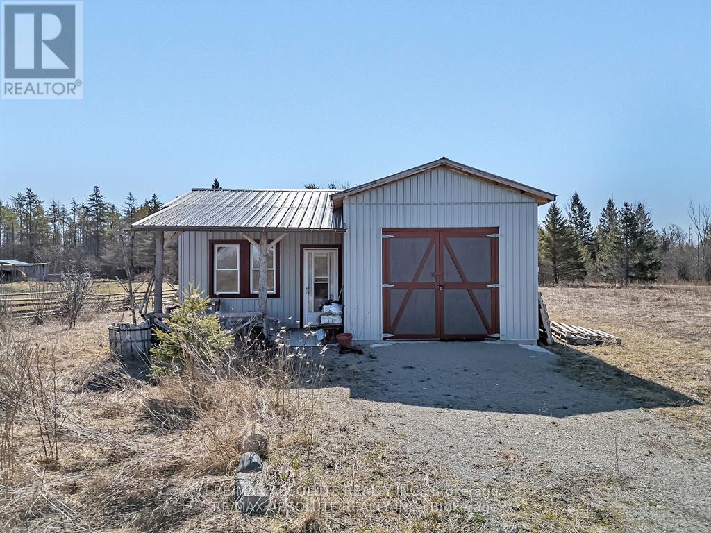 A two-car garage with a metal roof is situated in a field.