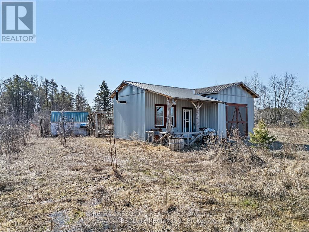 A metal building with a porch and a trailer in the background.