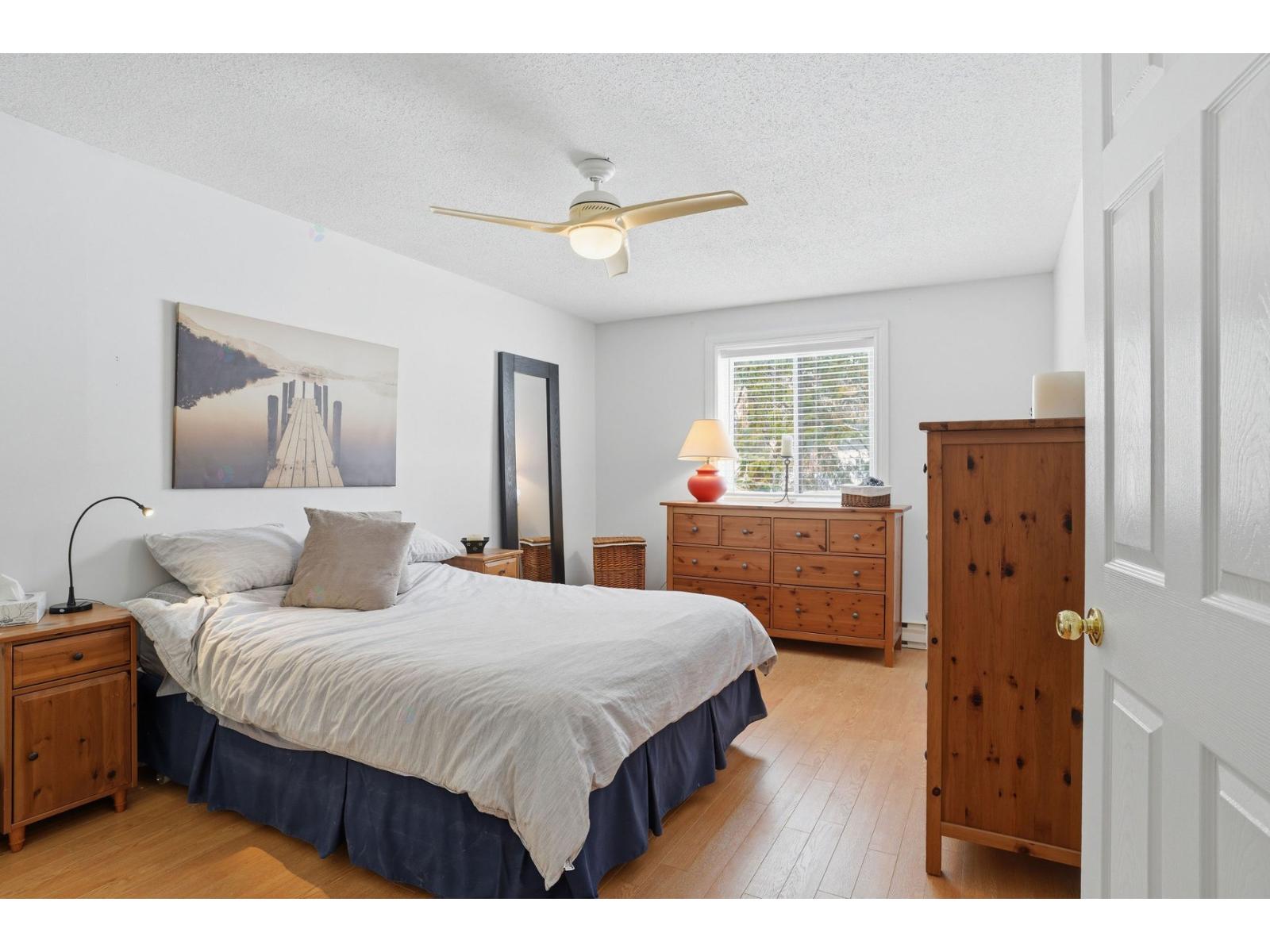 A bedroom with a bed, dresser, and a painting on the wall.