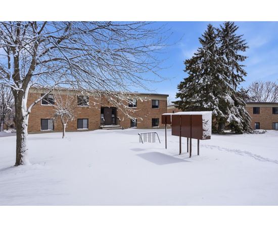 A snowy landscape with a building and trees.