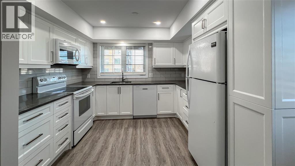 A modern kitchen with white cabinets and a refrigerator.