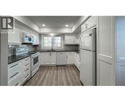 A modern kitchen with white cabinets and a refrigerator.