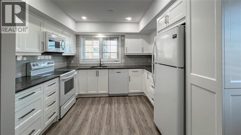 A modern kitchen with white cabinets and a refrigerator.