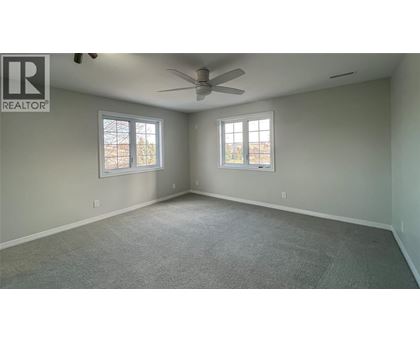 A spacious room with a ceiling fan and two windows.