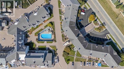 A bird's eye view of a residential area with houses, roads, and a swimming pool.