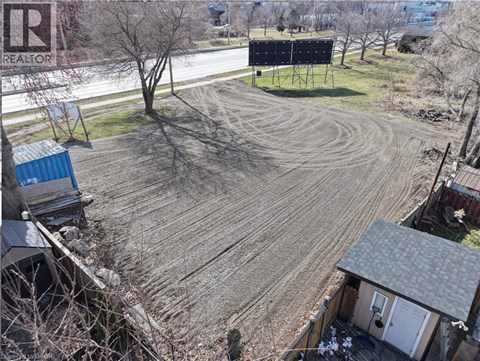 A large empty field with a house and a tree in the background.