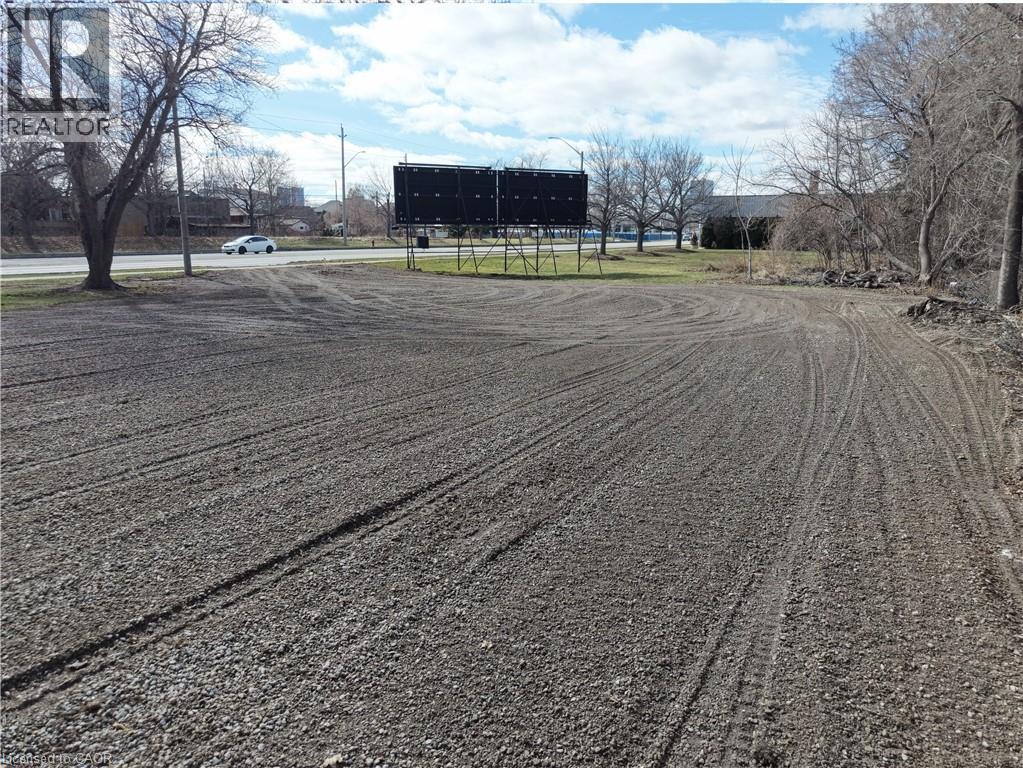 A large billboard stands in a field with tire tracks in the mud.