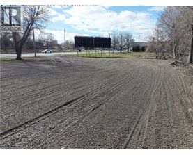 A large billboard stands in a field with tire tracks in the mud.