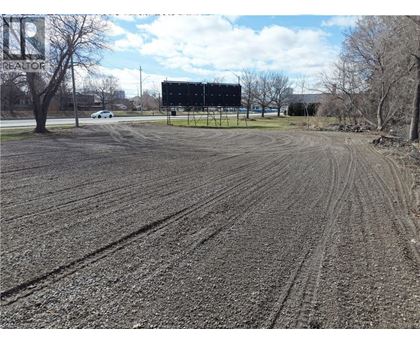 A large billboard stands in a field with tire tracks in the mud.