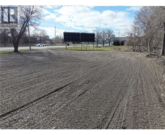 A large billboard stands in a field with tire tracks in the mud.