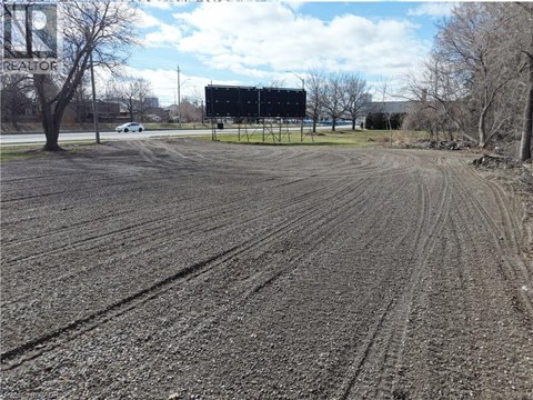 A large billboard stands in a field with tire tracks in the mud.