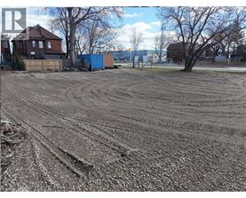 A dirt field with tire tracks in the foreground and a blue shipping container in the background.