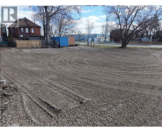 A dirt field with tire tracks in the foreground and a blue shipping container in the background.