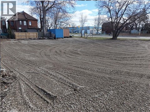 A dirt field with tire tracks in the foreground and a blue shipping container in the background.