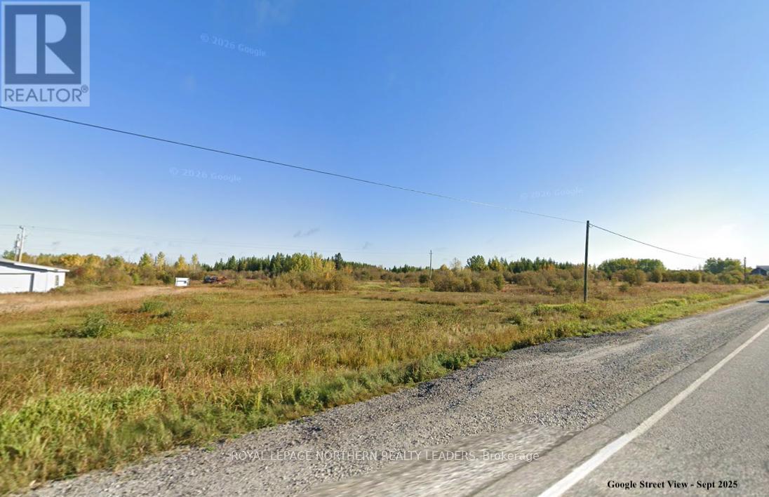 A gravel road stretches into the distance with a clear blue sky above.