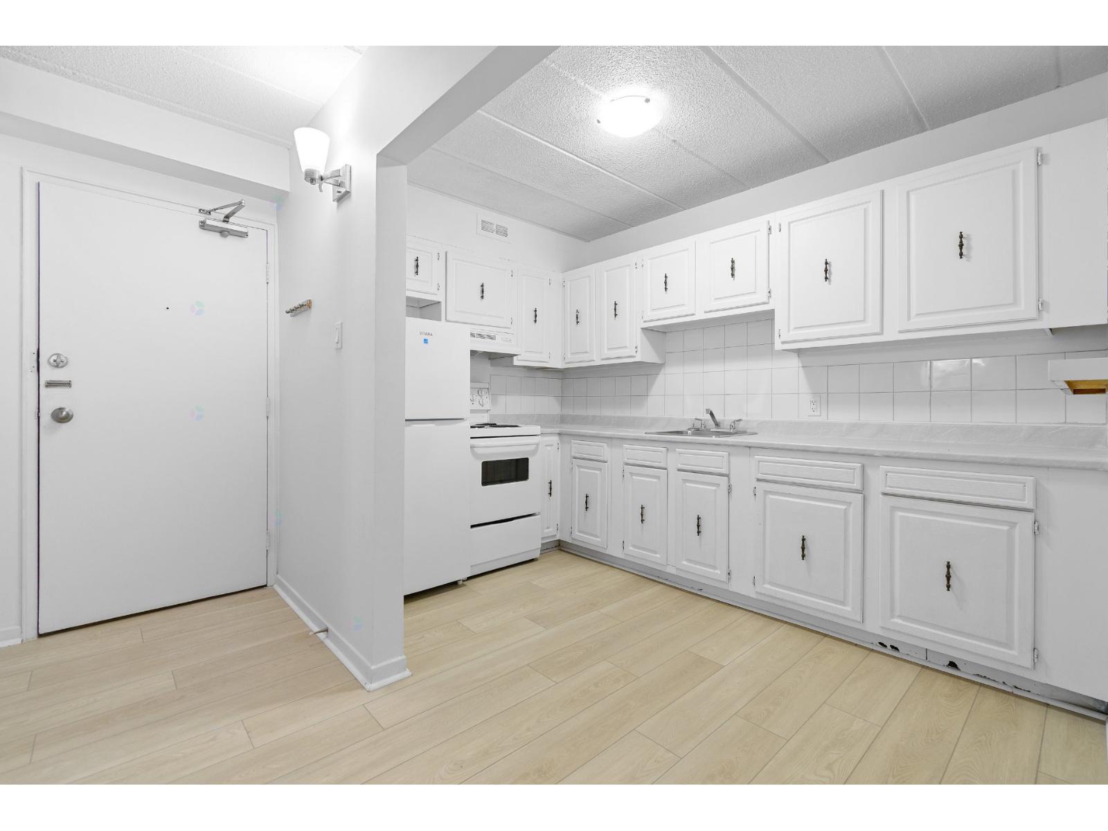 A white kitchen with wooden floors and white cabinets.