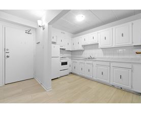 A white kitchen with wooden floors and white cabinets.