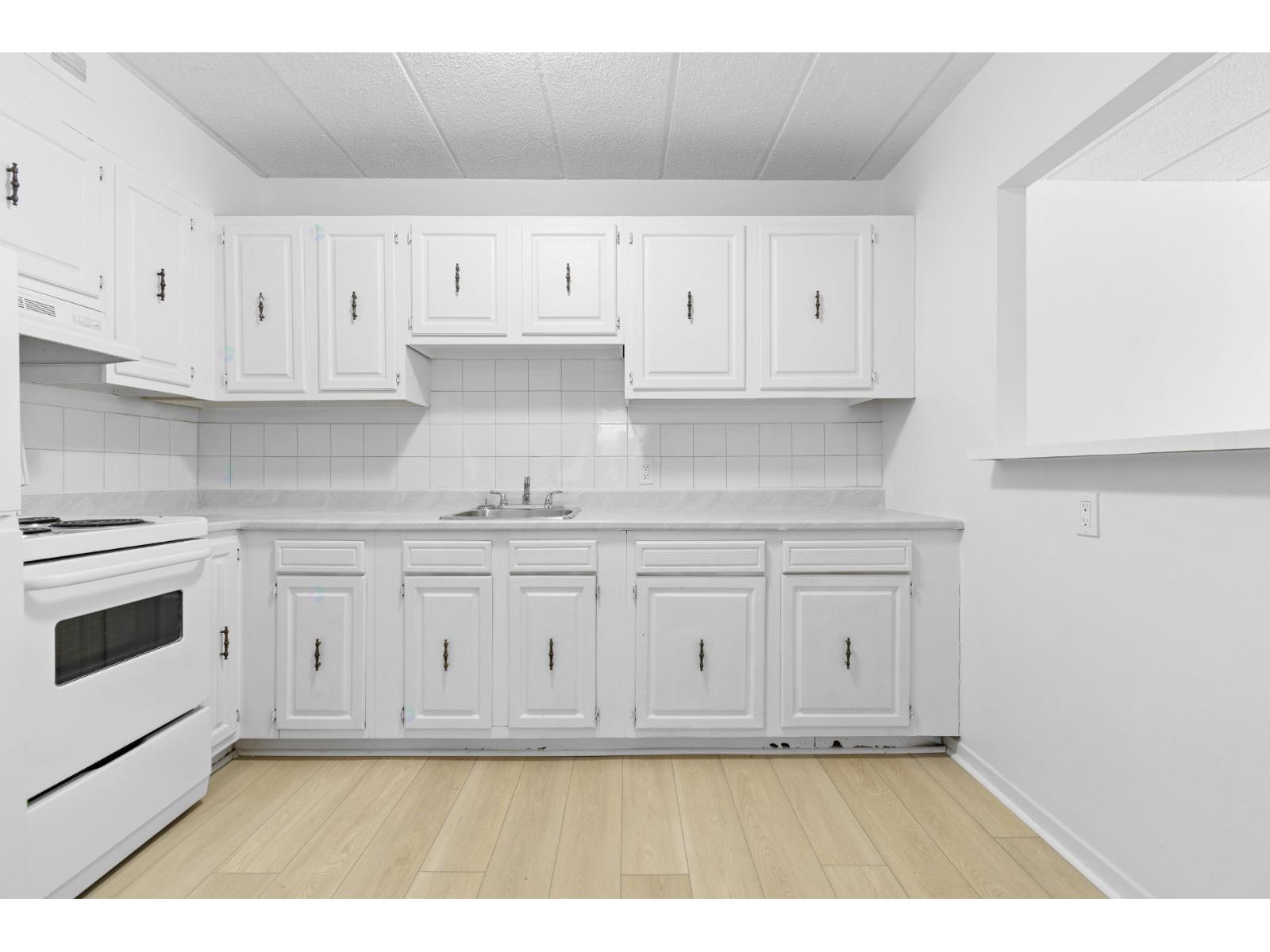 A kitchen with white cabinets and a white stove.