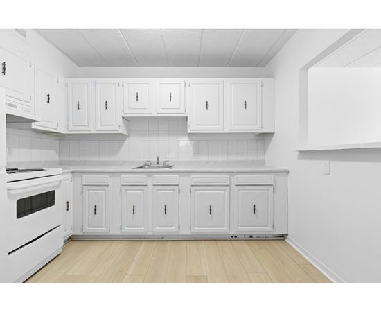 A kitchen with white cabinets and a white stove.