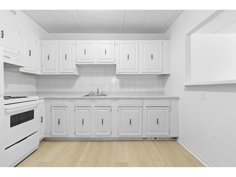 A kitchen with white cabinets and a white stove.