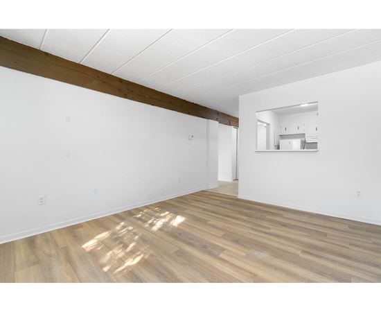 A room with wooden flooring and white walls.