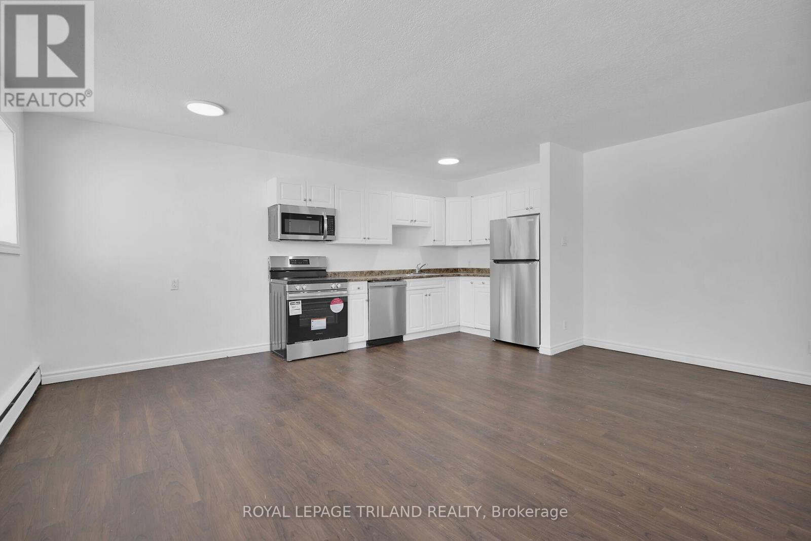 A spacious kitchen with white cabinets and a wooden floor.