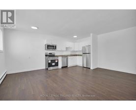 A spacious kitchen with white cabinets and a wooden floor.