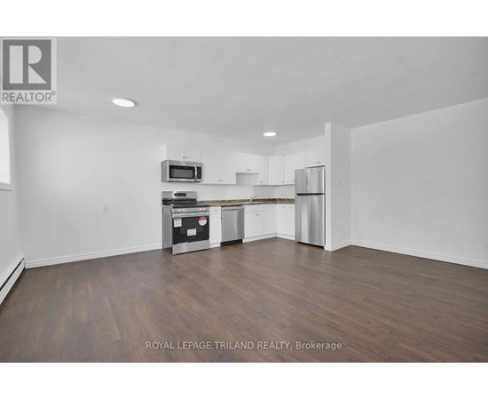 A spacious kitchen with white cabinets and a wooden floor.