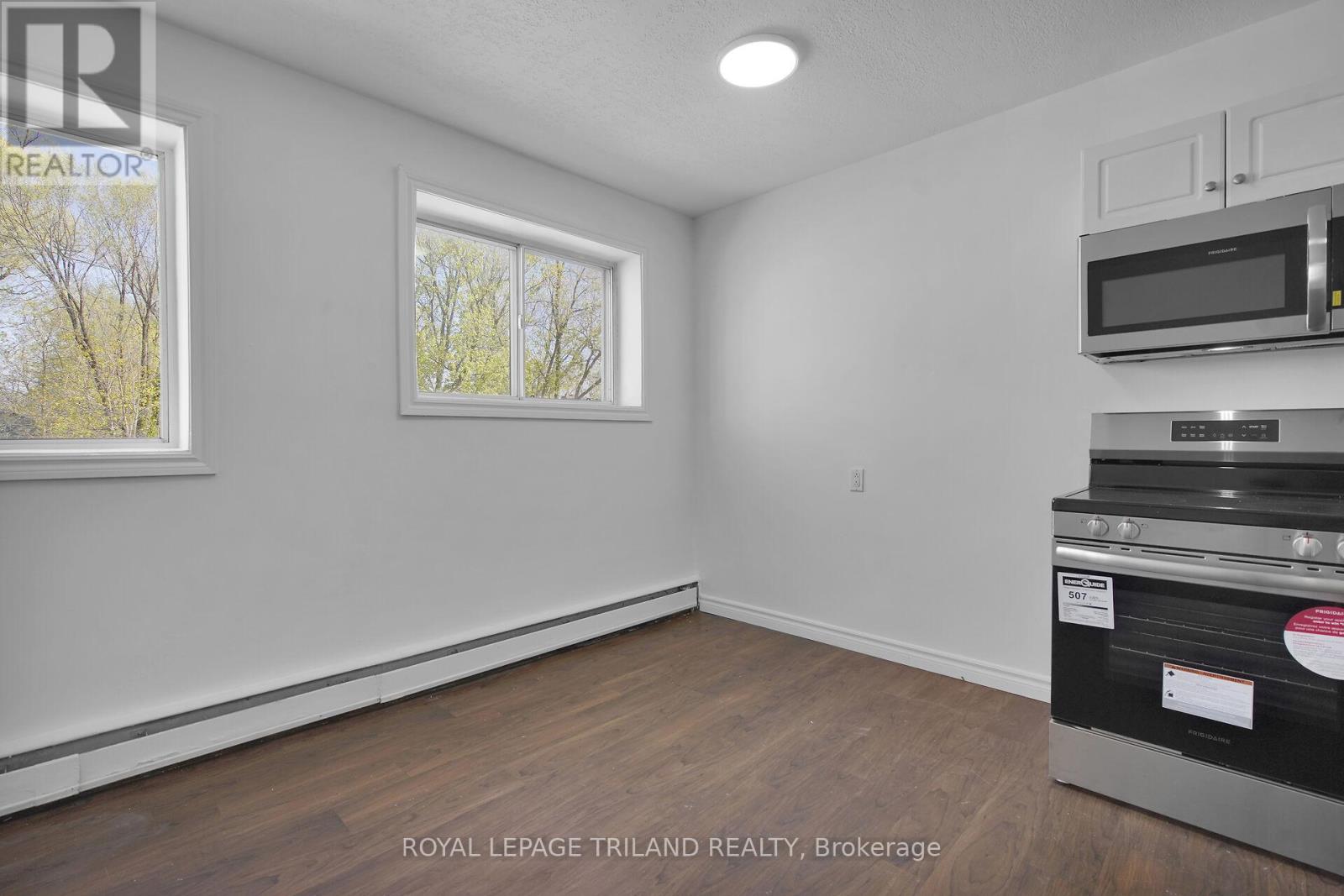 A white room with a window and a microwave on top of the oven.