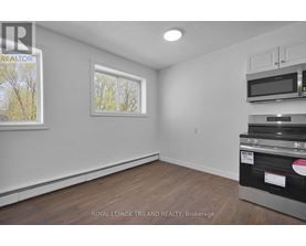 A white room with a window and a microwave on top of the oven.