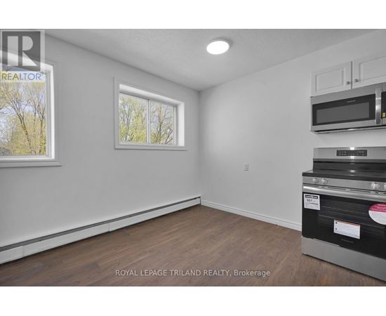 A white room with a window and a microwave on top of the oven.