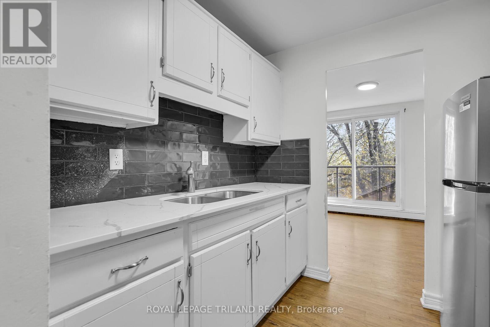 A kitchen with white cabinets and a black backsplash.
