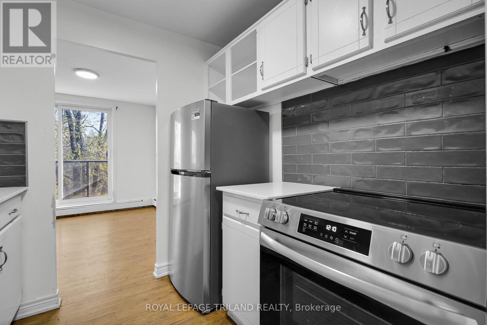 A modern kitchen with a stainless steel refrigerator and oven.