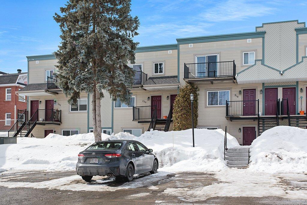 A car is parked in front of a building with snow on the ground.