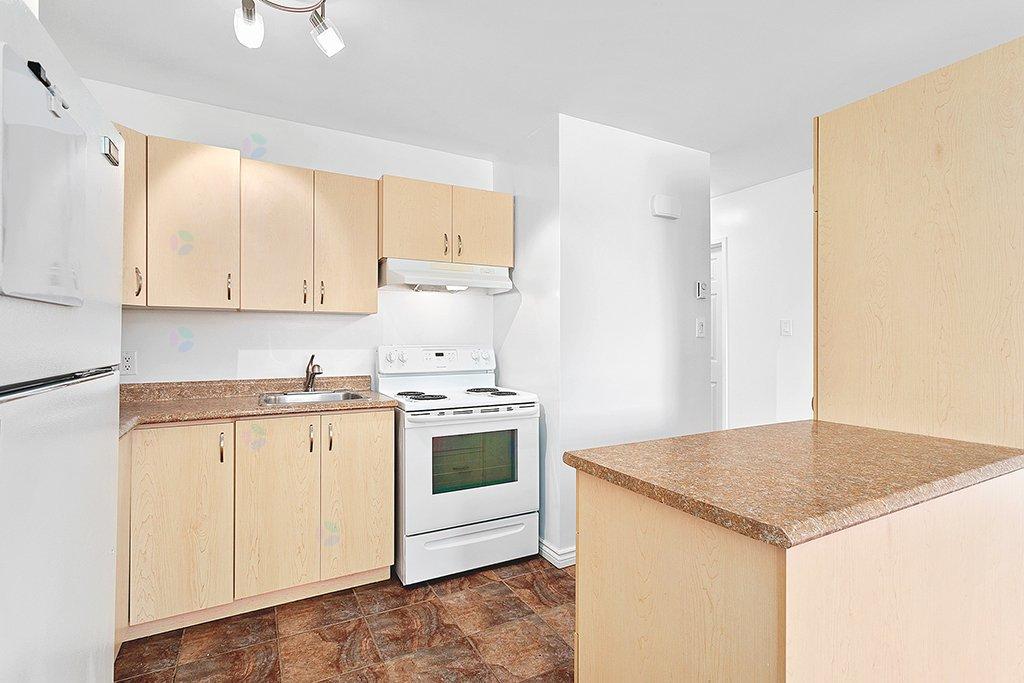 A kitchen with a white stove and cabinets.