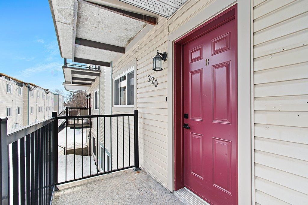 A red door with a black gate in front of a beige building.