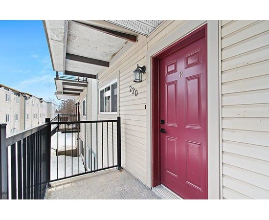 A red door with a black gate in front of a beige building.