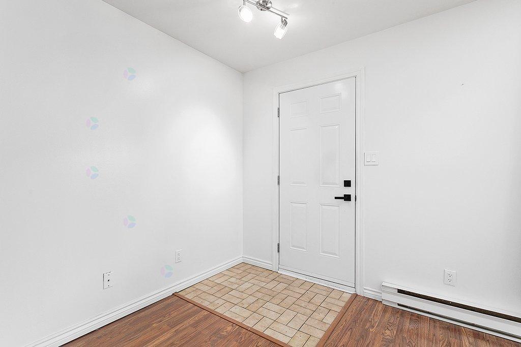 A white door is in a room with white walls and a wooden floor.