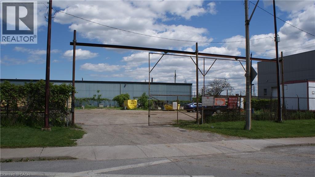 A REALTOR® sign is on a pole in front of a fenced area.
